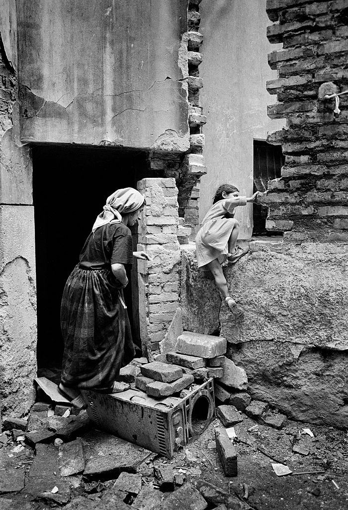 Muslim mother and her child enter their bomb damaged Sarajevo house on the frontline during the siege of Sarajevo in 1992.