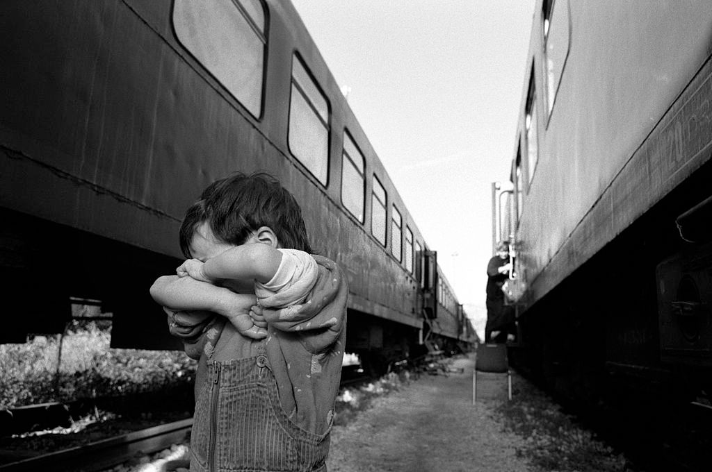 A small boy hides shyly away from the camera at a refugee camp made up of railway carraiges.