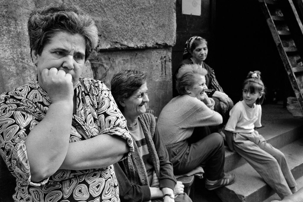 Mothers and children sit talking outside an apartment block during a break in shelling, July 1992.