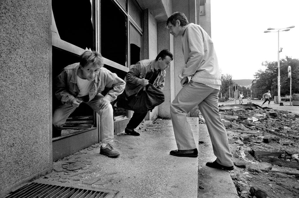 Men climb through broken shop windows out of the line of fire to avoid being shot by snipers, July 1992.