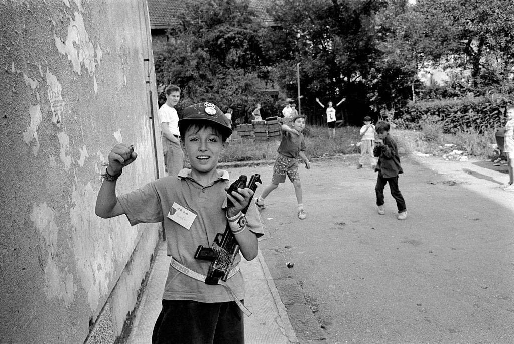 Children use empty amunition boxes as they play Serb against Bosnians during a break in the real life shelling of Sarajevo of 1992.