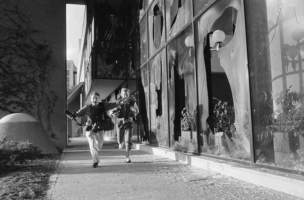 Photographers Paul Lowe and David Turnley run for cover beside the Holiday Inn hotel which was home to the media during the war, July 1992.