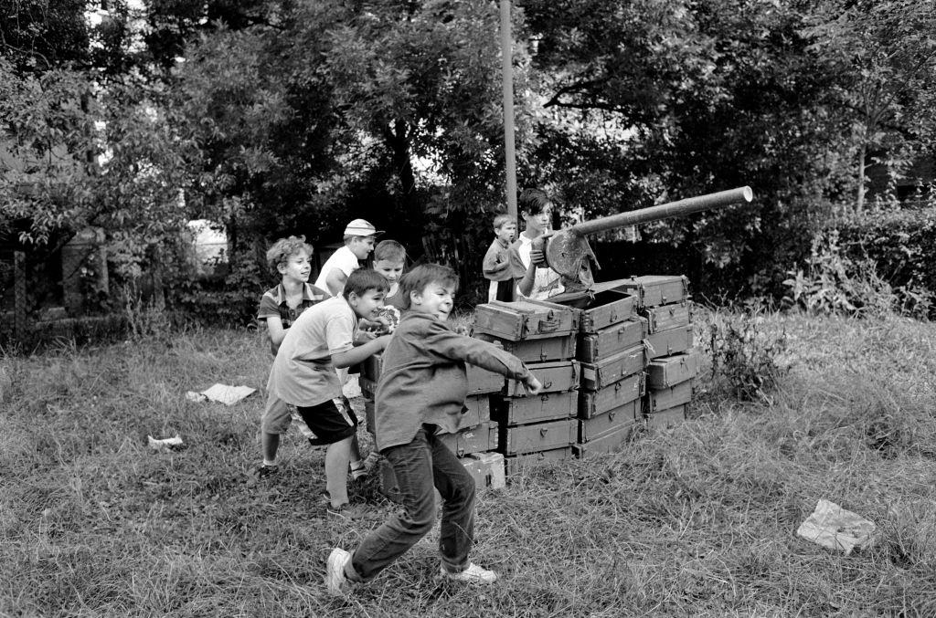 Children use empty ammunition boxes as they play Serb against Bosnians during a break in the real life shelling of Sarajevo of 1992.