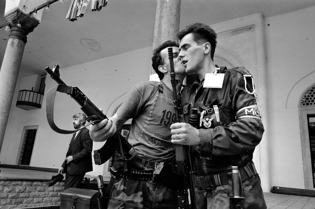 Bosnian fighters wish each other good luck and kiss goodbye after praying at a mosque before leaving to fight on the front line, 1992.