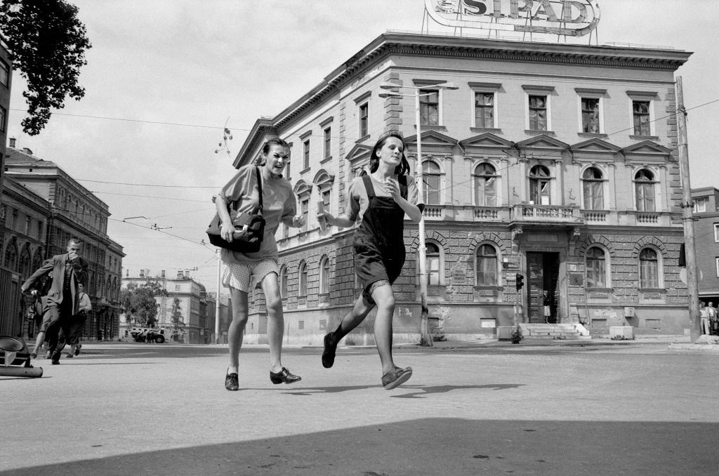Two teenage girls grimace with fear as they sprint across an intersection on Sniper Alley, July 1992.