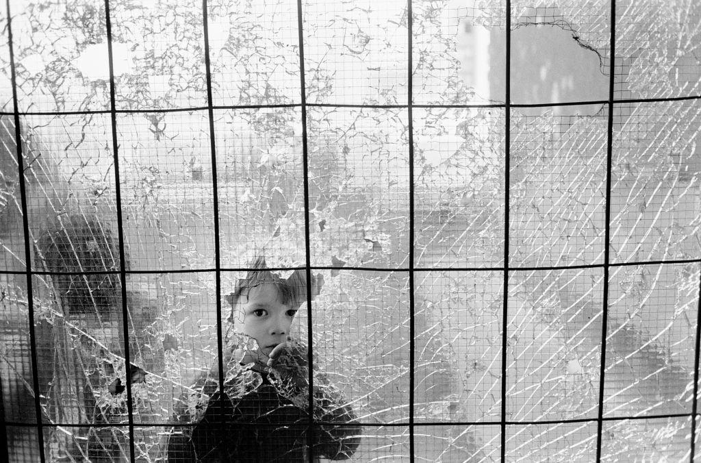 A small boy stares through a bullet riddled window in the Dobrinja suburb of Sarajevo.