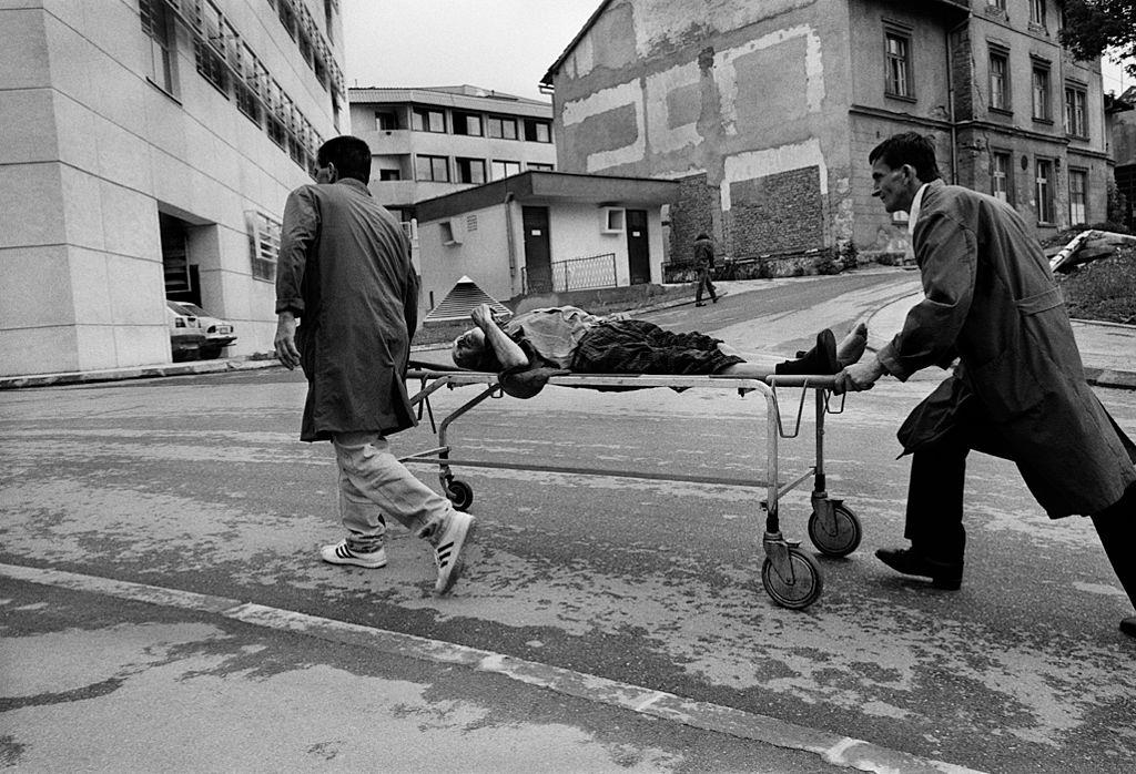 Porters from Kosovo Hospital rush a man wounded by a shell to the emergency room, during the Siege of Sarajevo, Bosnia, July 1992.