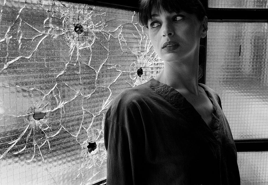 Former model Mirjana Deak photographed at home near windows shattered by sniper bullets during the siege of the city.