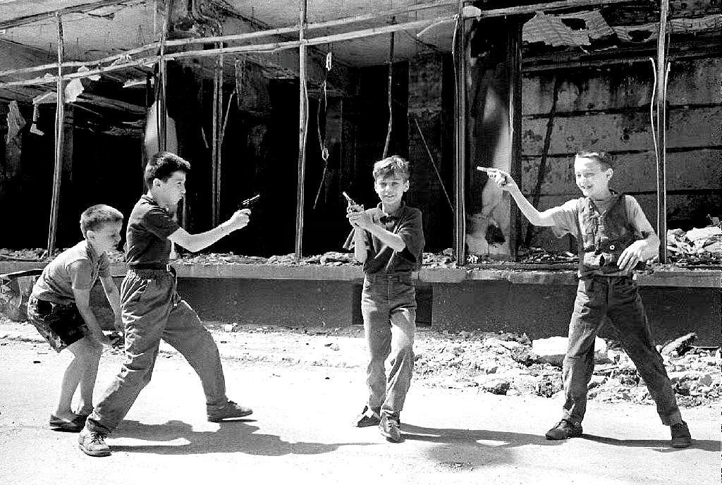 A group of young boys play with toy pistols in front of a burned building in Sarajevo 19 August 1992.