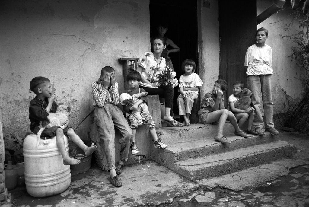 A mother from a poor family sits outside her home with eight of her ten children, May 1994.