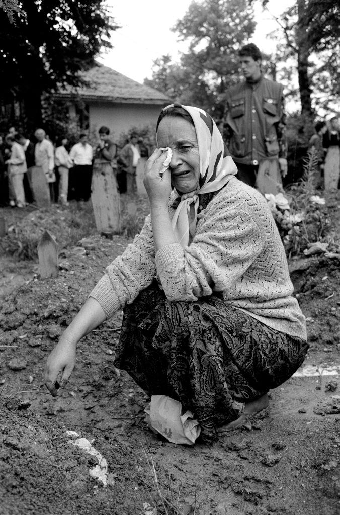 A woman grieves at her relative's grave after his burial in a Sarajevo cemetery, 1994.