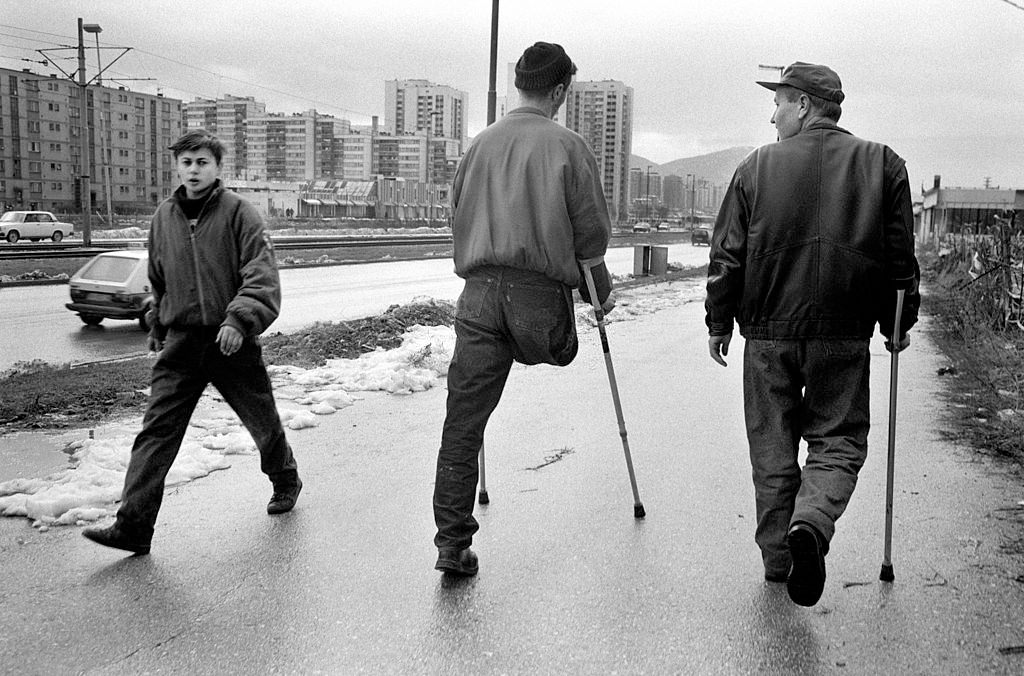 An amputee on crutches walks along the main road known as Sniper Alley, 1995.