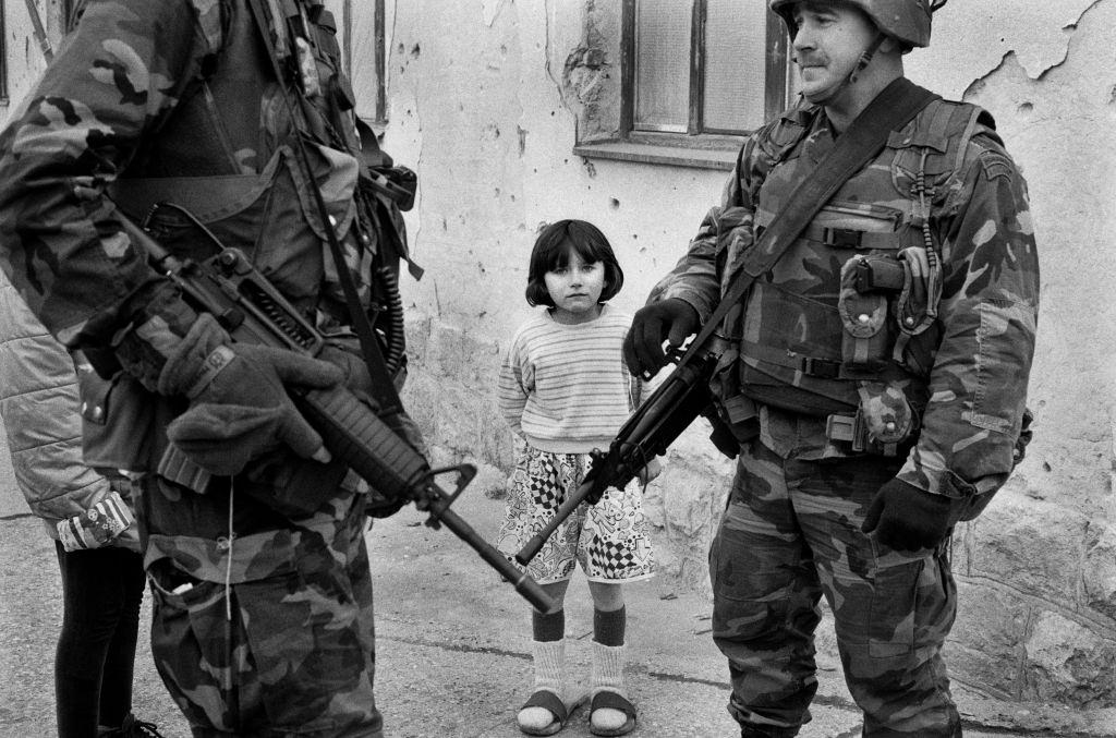 A little girl watches heavily armed US Special Forces on patrol in Sarajevo after the ceasefire, 1996.