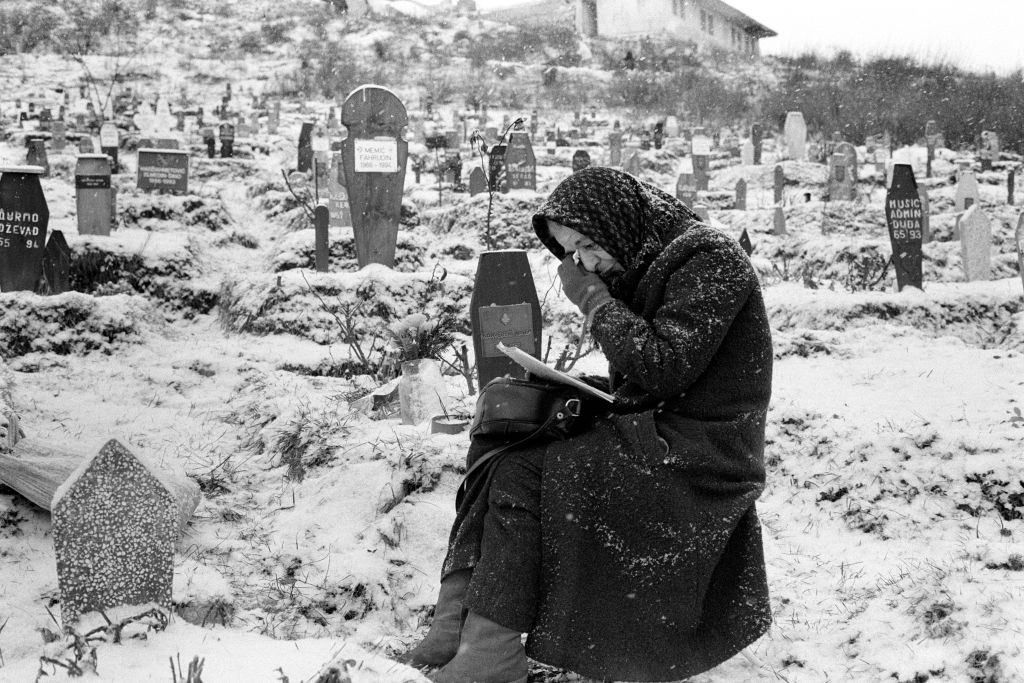 A woman grieves at the grave of her son in a snow covered Sarajevo cemetery, 1995.