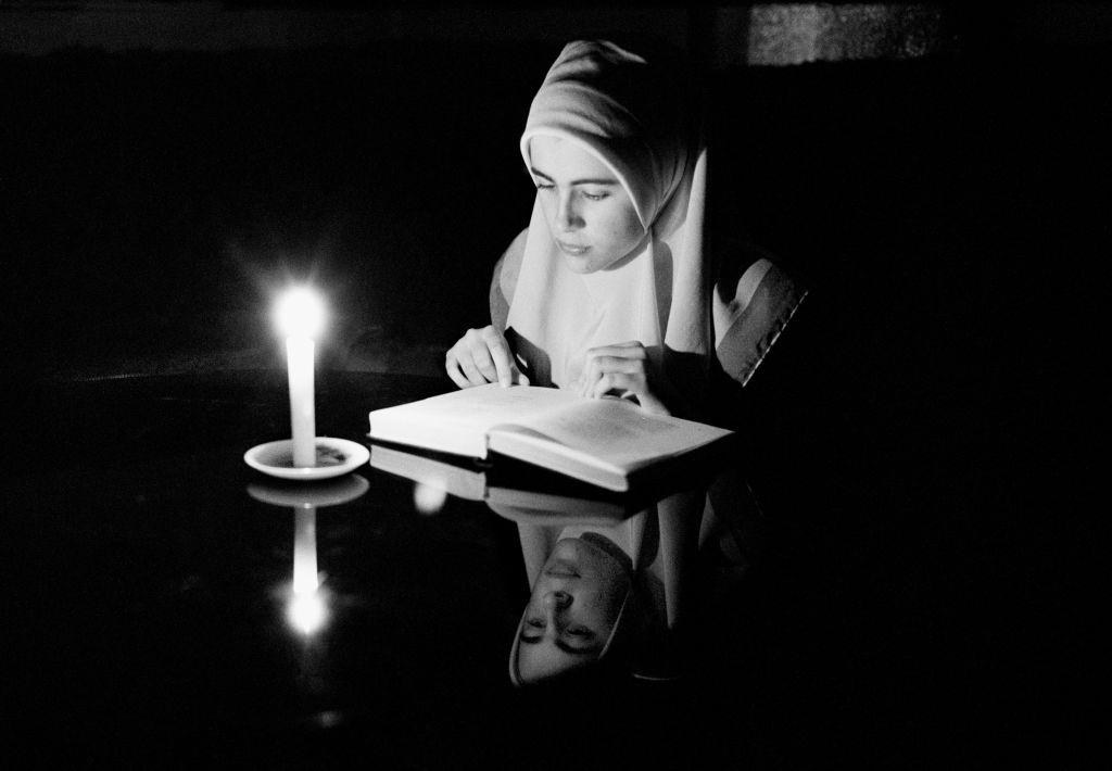 A Bosnian muslim girl studies the Koran by candlelight during the 47 month long siege of Sarajevo.
