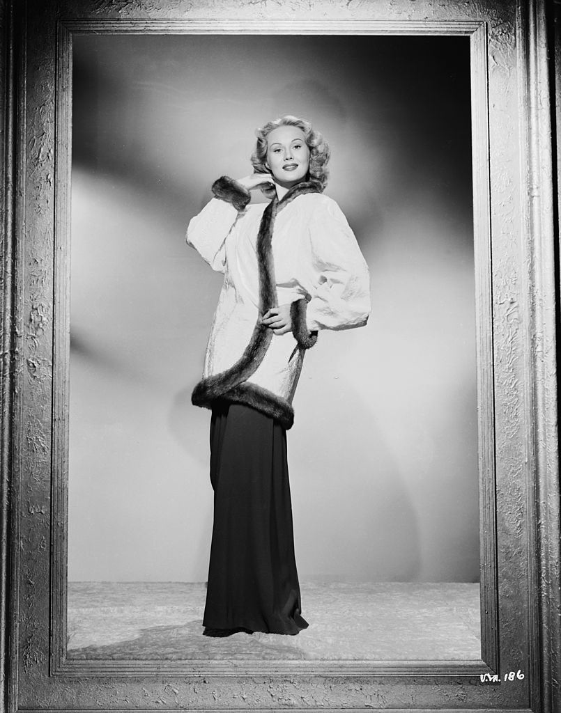 Virginia Mayo wearing a fur-trimmed jacket and loose-fitting trousers, 1950.