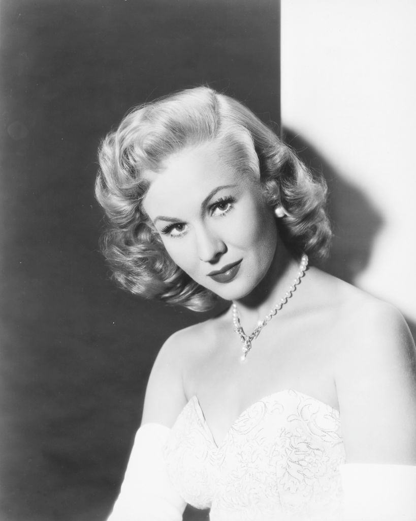 Virginia Mayo wearing white shoulderless dress with a diamond necklace, 1950.