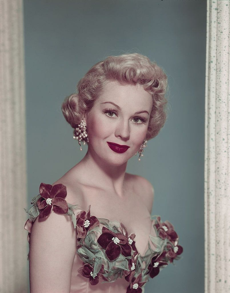 Virginia Mayo wearing elaborate pearl ear rings and a corset dress, 1950.