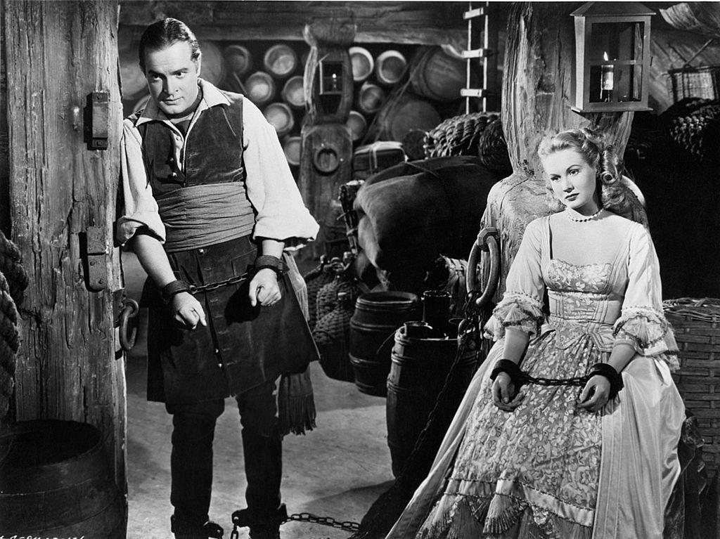Virginia Mayo and Bob Hope, chained at the wrist and ankle, are imprisoned in a warehouse in a scene from the movie 'The Princess and the Pirates', 1944.