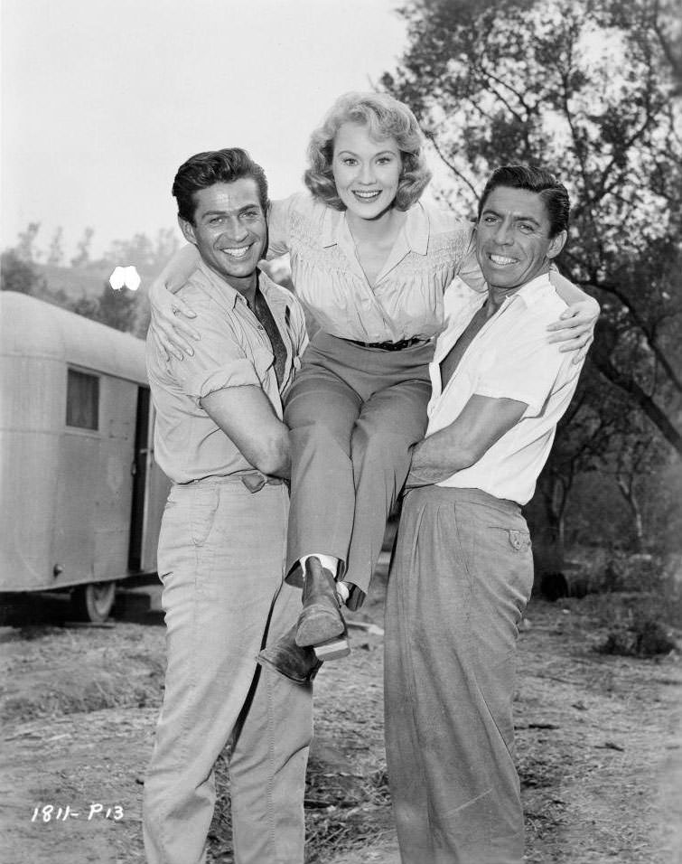 George Nader holds up Virginia Mayo with Michael Pate on set of the film 'Congo Crossing', 1956.