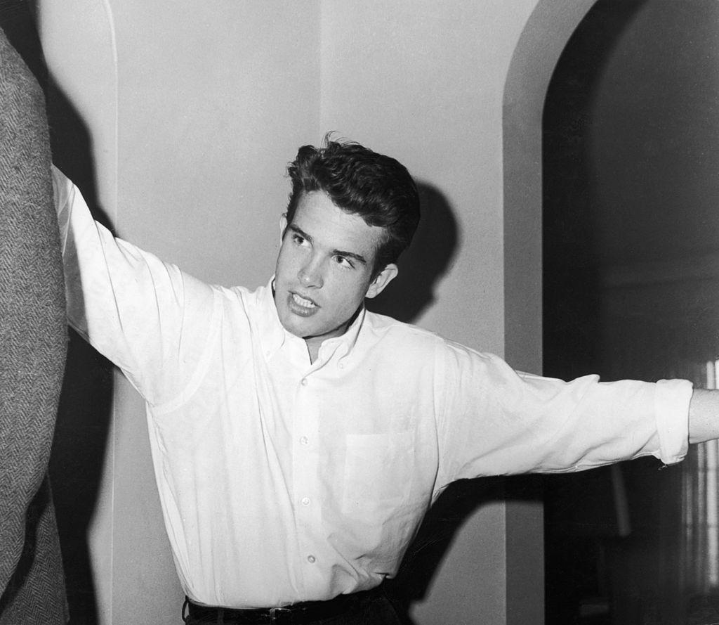 Warren Beatty wears a white button-down shirt in his apartment, 1955.