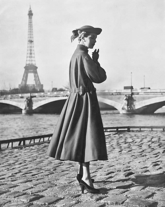 Joan Olson in loose coat of geranium-red wool, the below-the-waist belt gathers the back pleats, by Jacques Fath, 1953