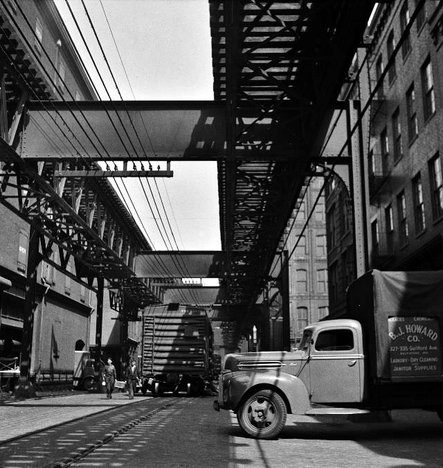 Trucks and trains unloading goods underneath an elevated trolley, Baltimore, Maryland, April 1943