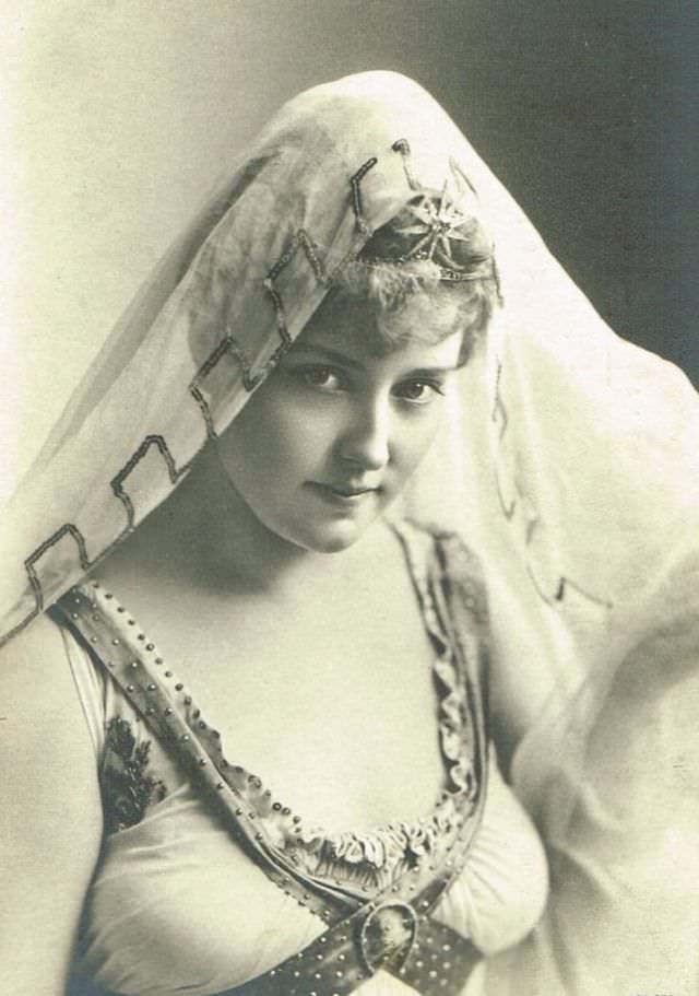 Lillian Russell wearing a lace and crochet princess-style gown, accessorized with an aigrette feather-trimmed hat, 1905.
