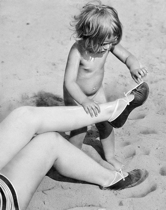 Summer on the beach. A little girl opened the laces of her mother's slippers, 1929