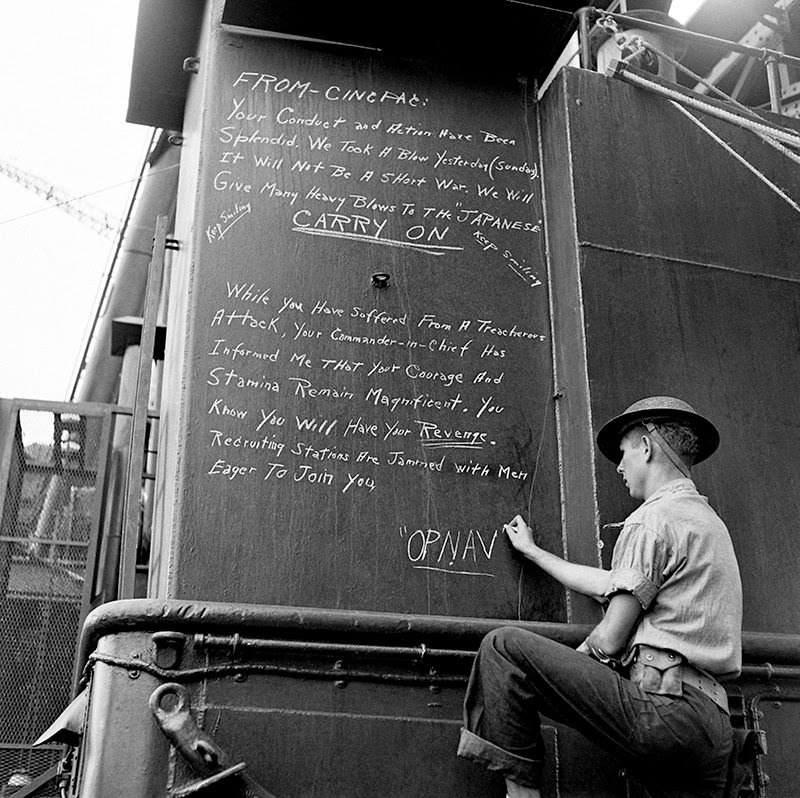 A sailor chalks a message to America's fighting men from the Office of the Chief of Naval Operations on a warship at Pearl Harbor.
