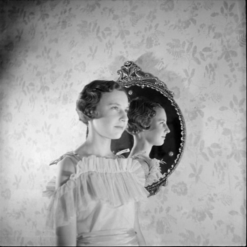 A young woman standing, in profile, in front of a mirror