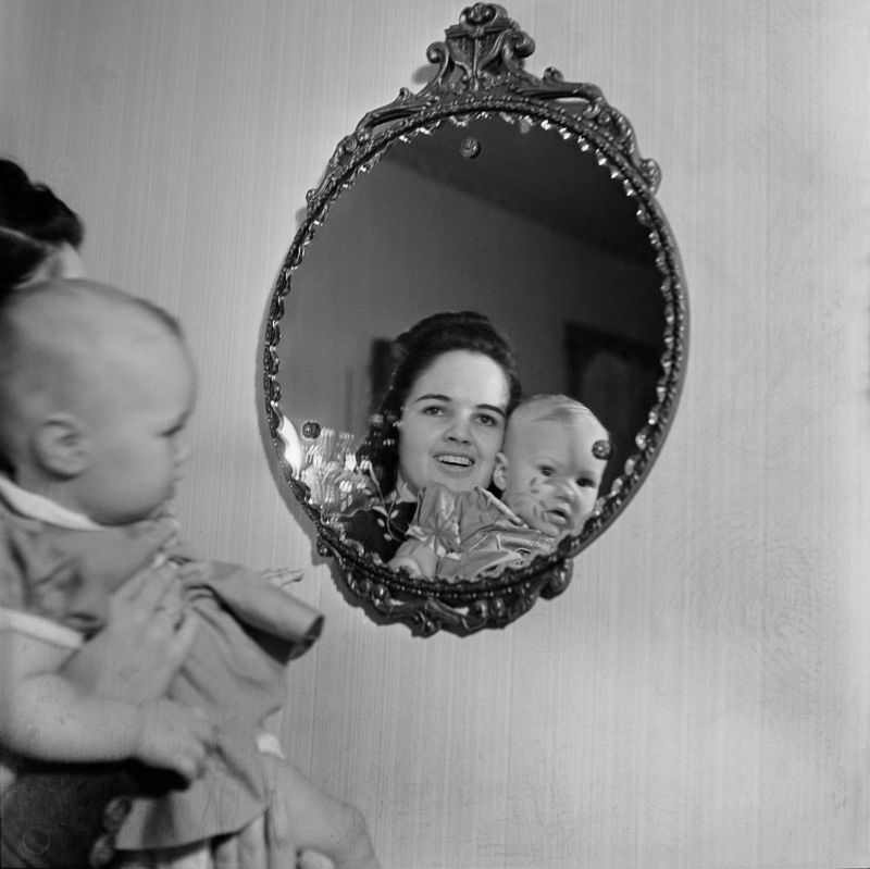 A woman holding woman holding an unidentified infant girl in front of a mirror