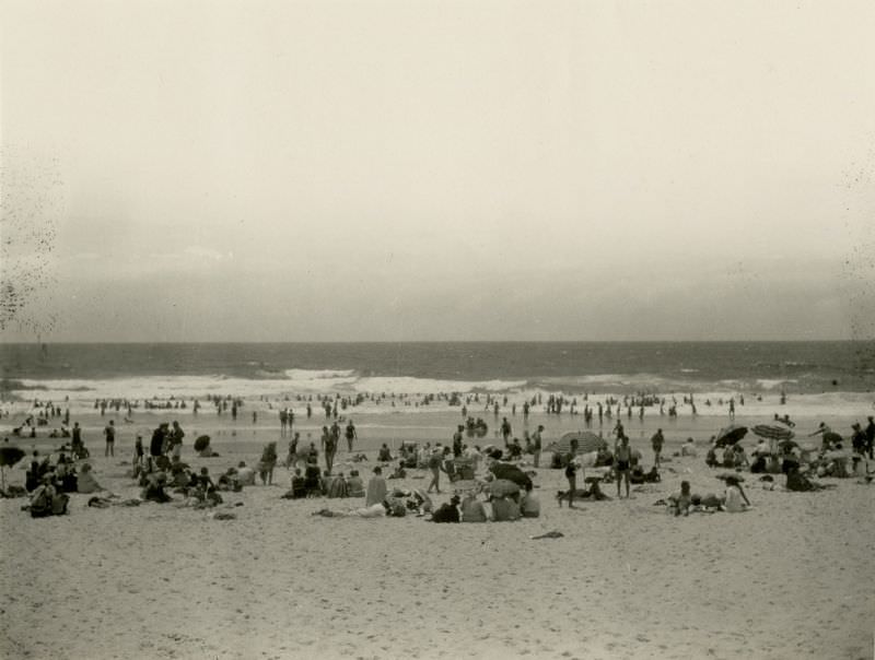 Locals and tourists sun bathing and surfing at Main Beach in Southport, 1930s