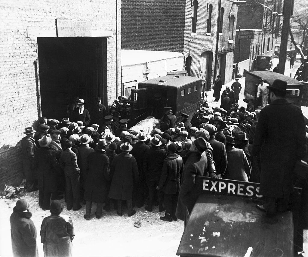 Onlookers watch as police remove the bodies of the victims of an execution style murder from the scene at 2122 North Clark Street in Chicago.