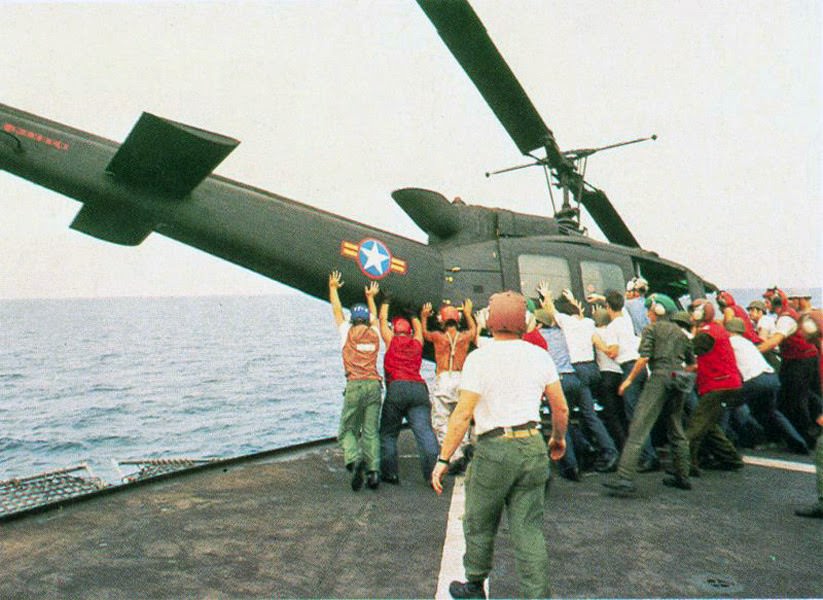 Japan ESouth Vietnamese UH-1H being pushed overboard to make room for a Cessna O-1 landing.