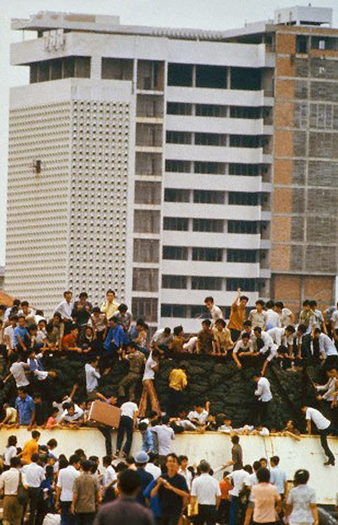 South Vietnamese clamber aboard barges in the port of Saigon in an attempt to escape from advancing North Vietnamese troops on the day of the Fall of Saigon.