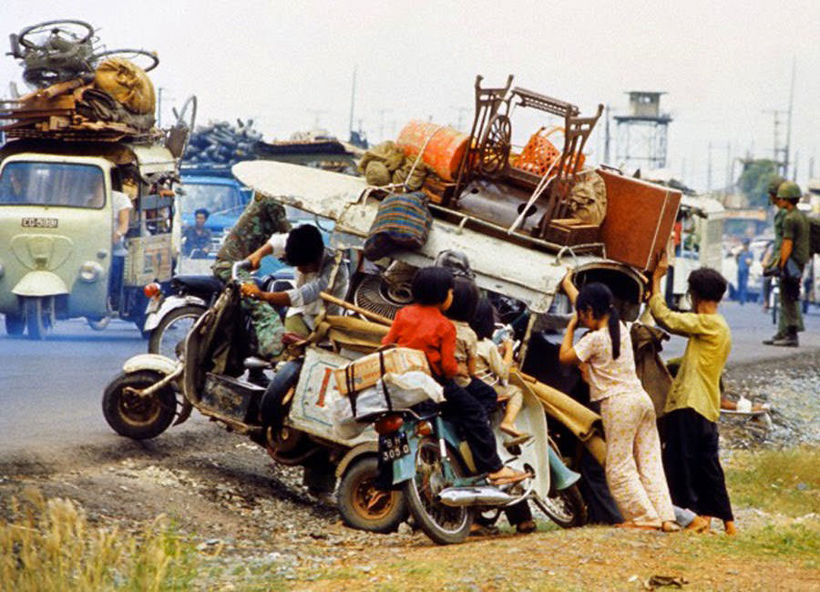 Vietnamese refugee family fleeing advancing North Vietnamese Communists try to push their laden scooter back onto Highway 1 outside Saigon