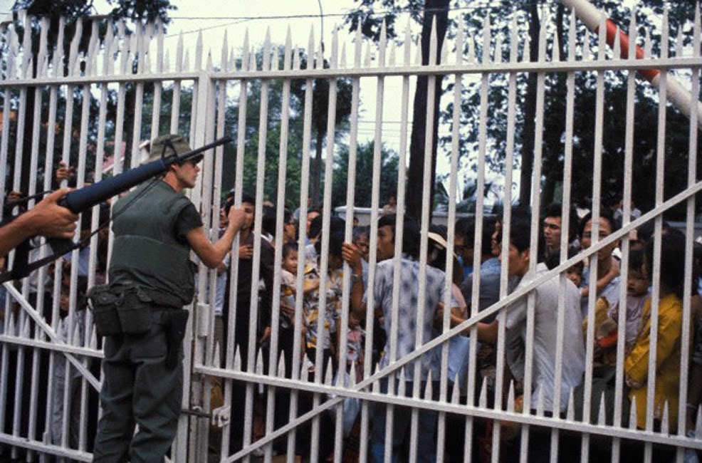 Desperate and frightened South Vietnamese try to convince US Marines guarding the American Embassy to let them into the compound hoping that they will be evacuated by helicopter.