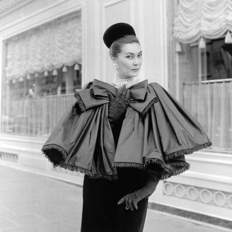 Alla in fringed satin capelet tied in large bow worn over slim velvet dress by Yves Saint Laurent, photo by Willy Maywald, Paris, 1959