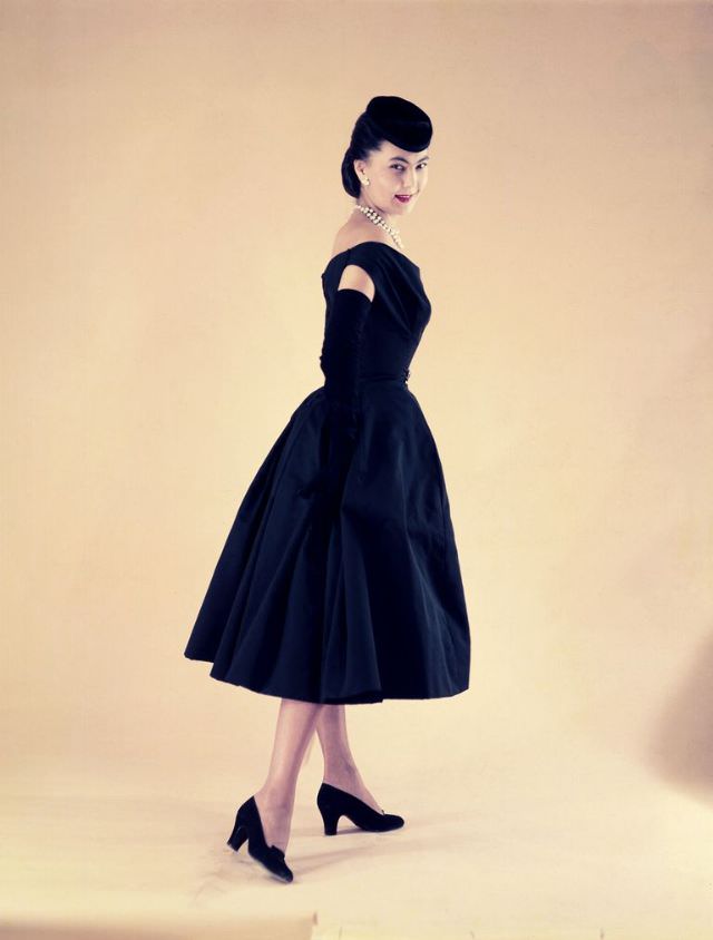 Alla in Christian Dior's midnight blue taffeta dress with draped bodice worn with a small velvet cap tilted forward, Paris, circa 1950s