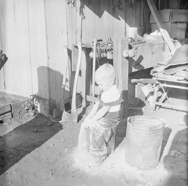 Boy sitting on a pale in front of a workbench