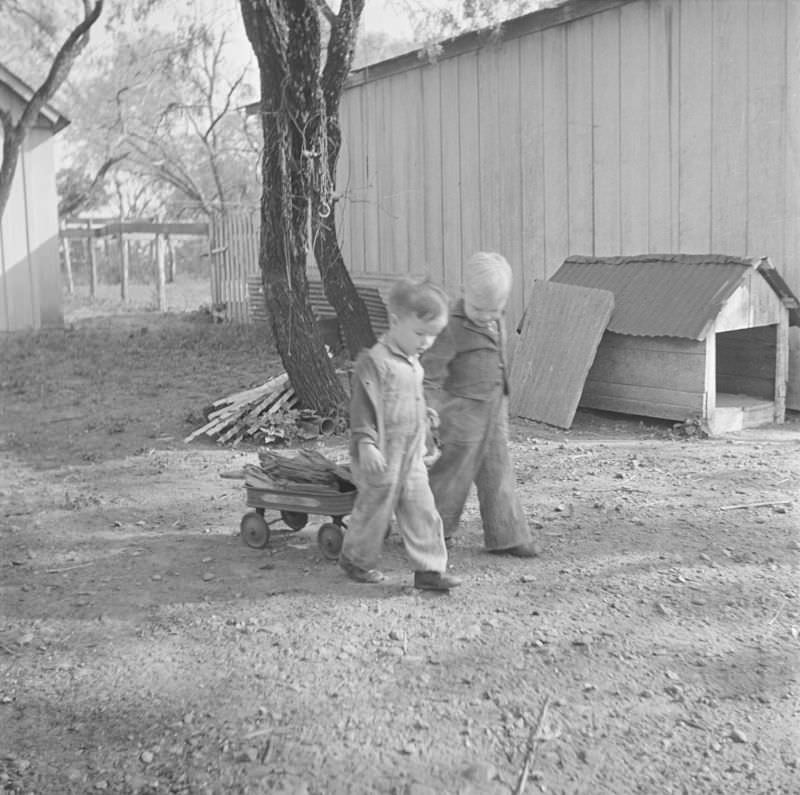 Two boys wheel around a small wagon of wood together