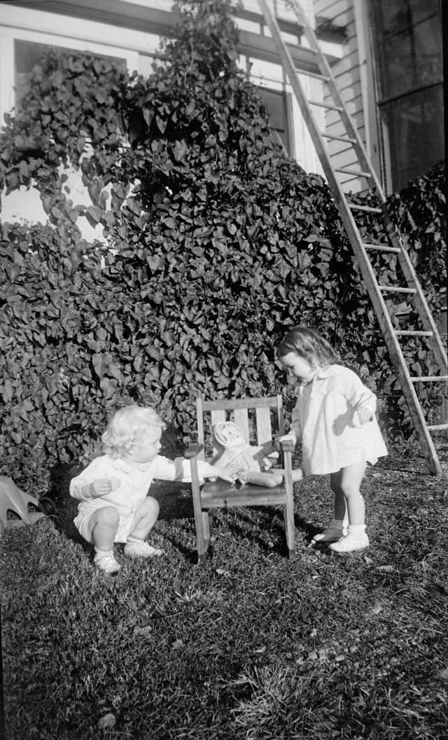 Two little girls standing next to a child-size chair with a doll on it