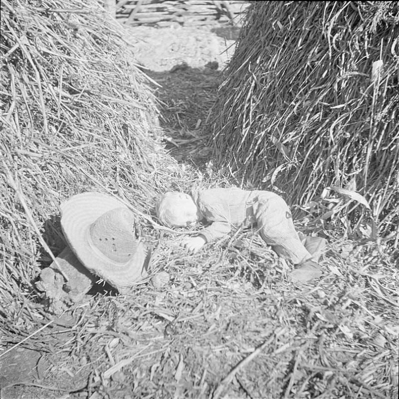 Boy laying down in between two haystacks