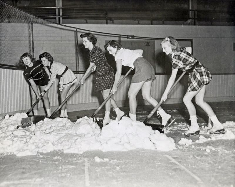 Girls shovel ice on rink