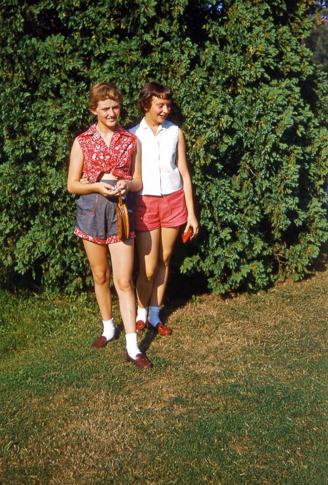 Two teenage girls by large shrub