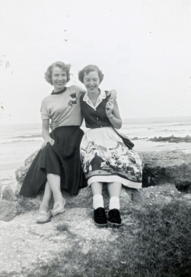 Two young women on rock by beach