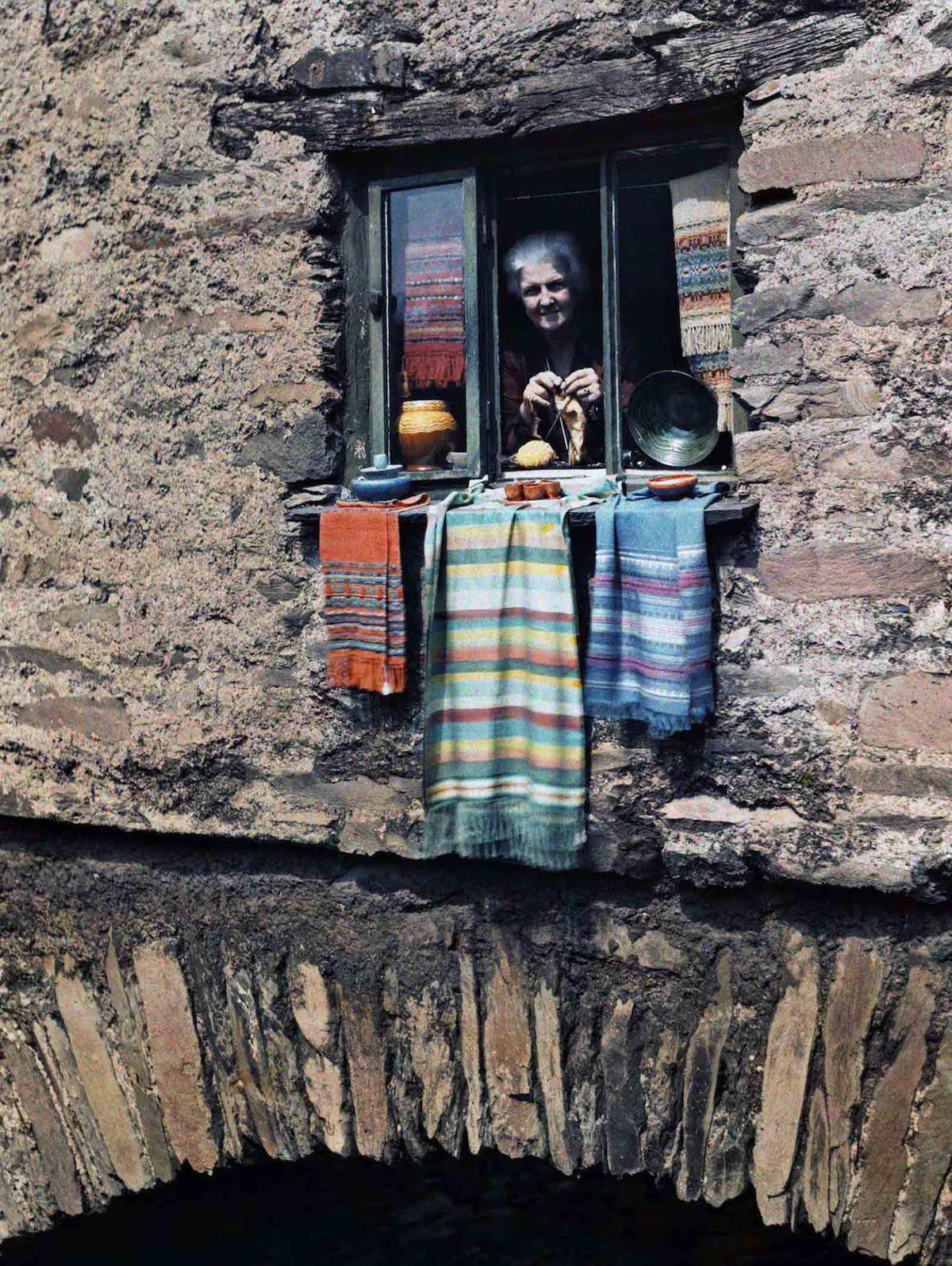 A woman sticks her head out of her bridge house window, in Ambleside, Lake District, Cumbria, England.