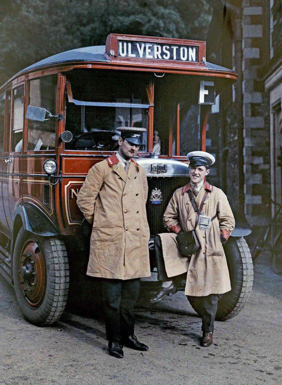 Two bus drivers stand in front of a tour bus in Ulverston, Cumbria.