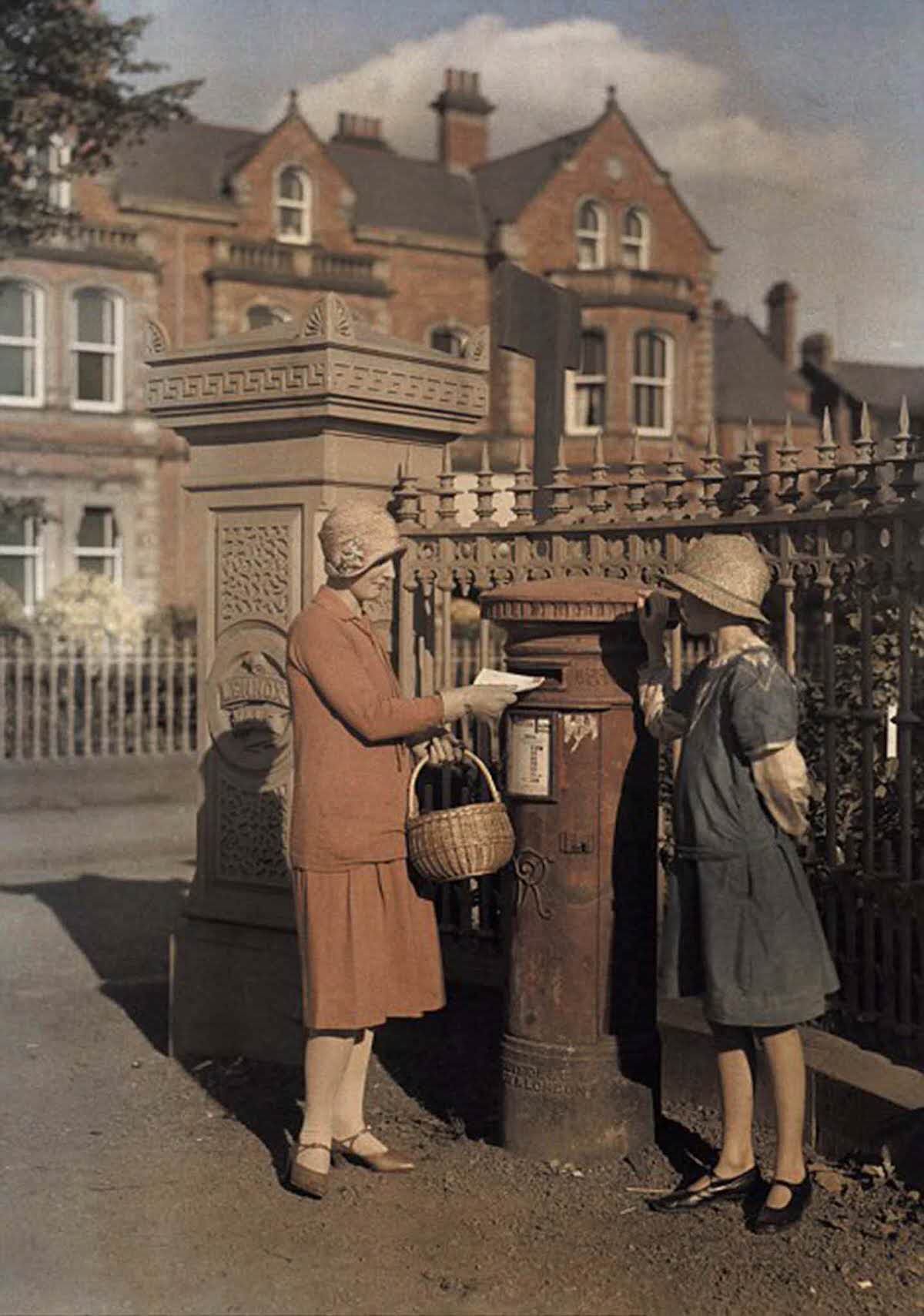 Two girls send a letter at a red pillar box in Belfast in 1927.